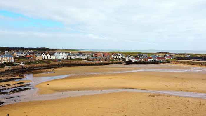 Aerial view of the tide receding in Elie Harbour, Scotland, with the adjacent village on the coastline.