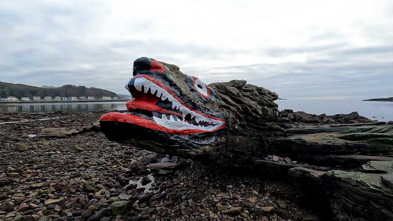 Достопримечательность Crocodile Rock на фоне моря и залива Millport Bay