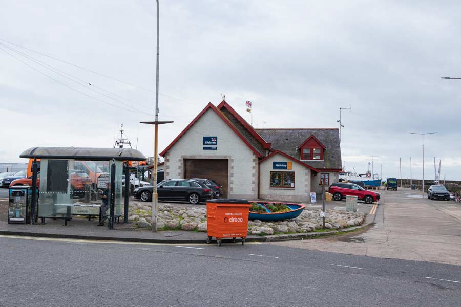 Здание спасательной станции RNLI и автобусная остановка у гавани в Анструтере